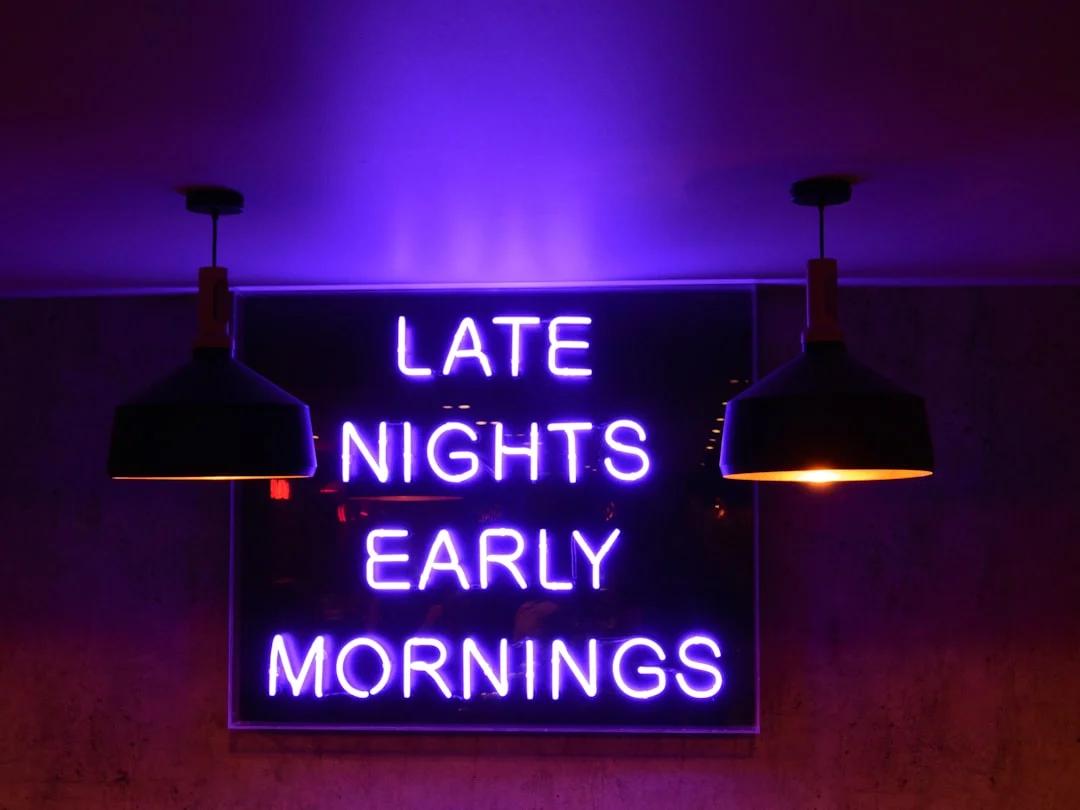 A warm-glowing custom LED neon sign reading a personal phrase mounted on a white plaster wall above a mid-century sideboard, photographed in a stylish living room at dusk